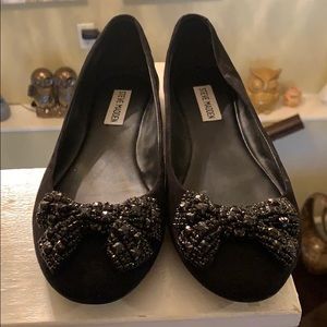 Black suede flats with rhinestone bow detail.